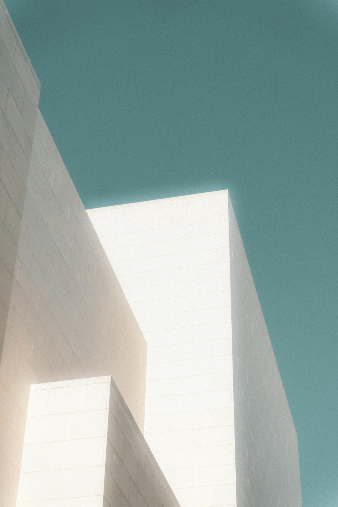 Helle, klare Architekturkanten vor ruhigem türkisfarbenem Himmel — Struktur und Präzision.